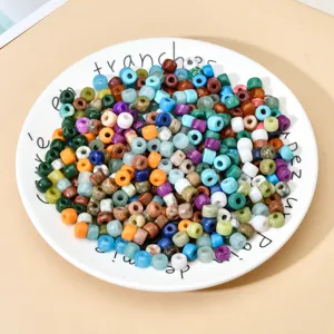 Nahaufnahme von bunten Stein- und Glasperlen mit großem Loch im weißen Teller für DIY-Schmuck.