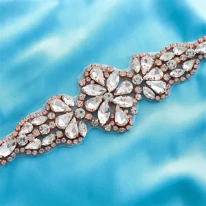 Detailed shot of sparkling rhinestone bridal belt applique with rose gold setting and clear stones.
