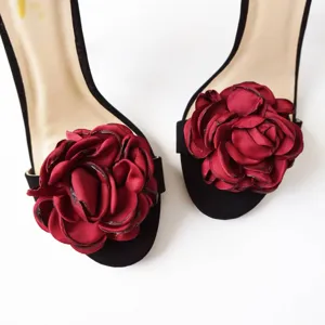 Black high heel sandals detail featuring large detachable burgundy fabric rose flower clips.