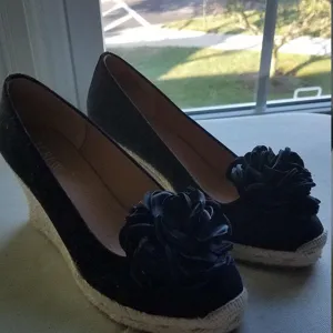 Black wedge espadrilles with large fabric flower toe decoration. Casual women's fashion shoes.