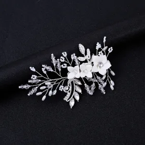 Nahaufnahme des silbernen Brauthaarkamms mit weißem Blumenkristall und Perlendetails.