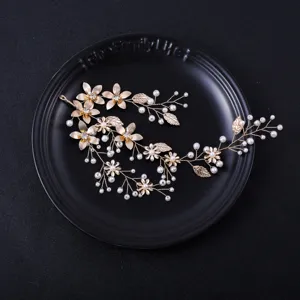 Detailed view of a gold floral pearl hair vine bridal headpiece with crystal and leaf accents.