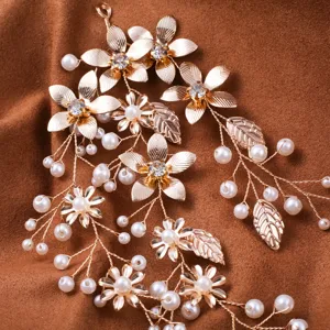 Close-up of elegant gold leaf and flower bridal hair vine with pearls and rhinestones.