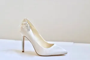 Détail élégant de soulier de mariée avec clip décoratif en perles et strass.
