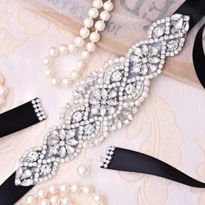 Dettaglio cintura da sposa in strass, decorazione con cristalli scintillanti e perle su nastro.