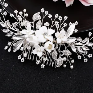 Eleganter Braut Haarkamm mit weißen Keramikblüten, funkelnden Kristallen und silbernen Blättern.