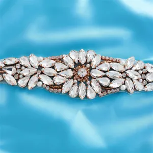 Close-up detail of bridal rhinestone applique with sparkling crystals on shiny blue satin cloth.
