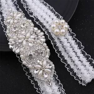 Detail view of white lace bridal garter set featuring sparkling rhinestones and faux pearls.