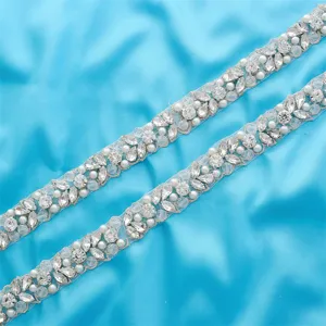 Close-up detail of bridal rhinestone belt trim, sparkling crystals and pearls on mesh.