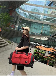 Outdoor urban lifestyle detail shot showing large capacity red and black duffel travel fitness bag.