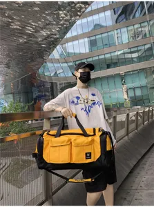 Urban outdoor lifestyle detail shot of a large yellow and black travel duffel bag with multiple pockets.