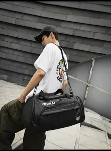 Detailed view of the black travel duffel bag being carried in an urban outdoor setting.