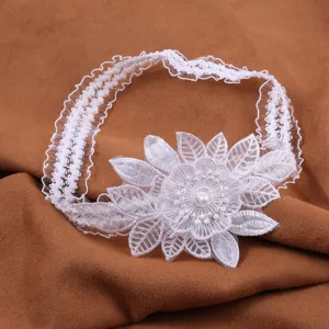White lace garter detail showing intricate floral embroidery and pearl center for wedding.