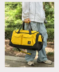 Detail shot of the large yellow duffel bag featuring front pockets and sturdy handles.