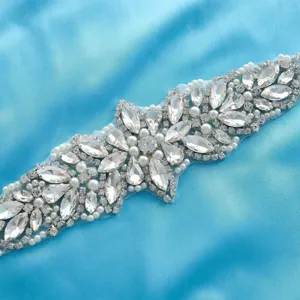 Rhinestone bridal belt detail close-up showing sparkling crystals and pearls on blue satin.