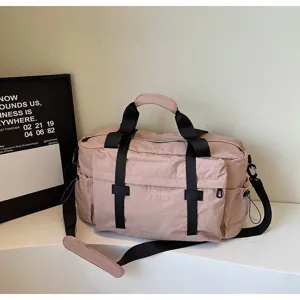 Roze reistas met zwarte riemen, grote sporttas en schoudertas handtas detailweergave.