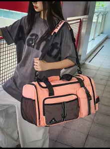 Detailed shot of the pink travel duffel bag with mesh side pockets and adjustable strap.