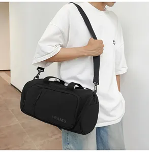 Detail view of a black travel duffel bag with front pocket, handle, and adjustable shoulder strap.
