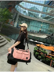 Outdoor detail shot of a pink and black travel duffel bag with multiple pockets and straps.