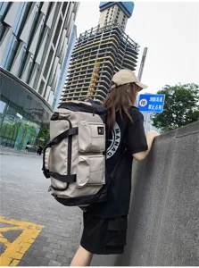 Outdoor lifestyle detail view of a large capacity travel duffel backpack in beige and black.