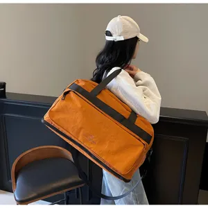 Dettaglio della borsa da viaggio arancione con tessuto impermeabile e robuste bretelle nere.