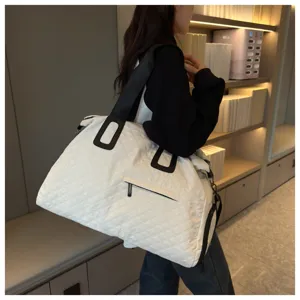 Large capacity white quilted travel bag detail, casual shoulder duffel for women on outdoor trips.