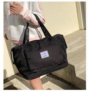 Vue détaillée du grand sac de voyage noir avec poche avant et poignées résistantes.
