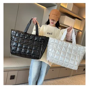 Detailed view of large capacity quilted puffer tote bags held by model in indoor setting
