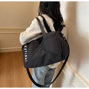 Details of black travel duffel bag showing strap, side zipper pocket and printed brand logo.