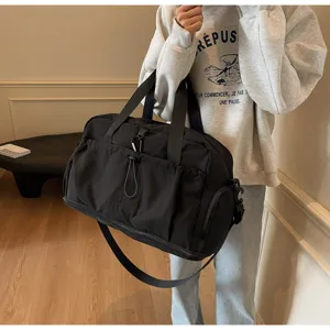 Detailed view of the black travel duffel bag, showing functional pockets in scene.