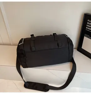 Black cylindrical gym duffel bag large capacity travel luggage sports bag with adjustable strap.