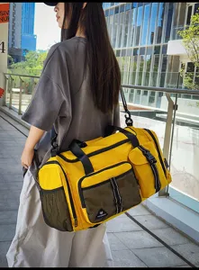 Large capacity yellow travel duffel bag detail, side view showing mesh pockets and black straps.