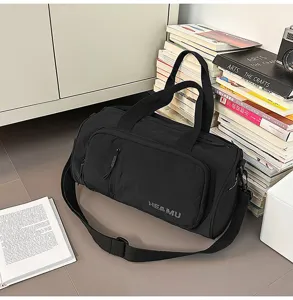 Detail view of the black travel duffel bag showing front pocket, sturdy handles and strap.