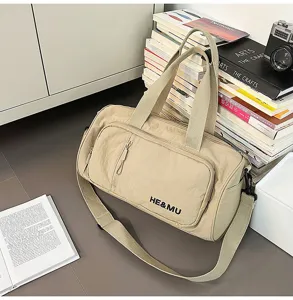 Detail shot of the beige travel duffel bag with front pocket, adjustable strap and handles.