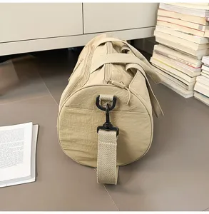 Detail shot of khaki travel duffel bag, showing durable fabric, strap and metal buckles.