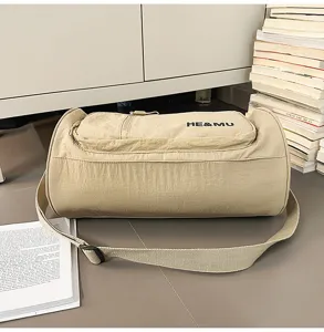 Khaki cylindrical travel duffel bag with shoulder strap and front zipper pocket detail.