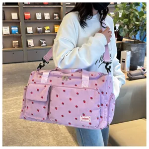 Detailed view of the cute strawberry print corduroy travel duffel bag with front pockets.