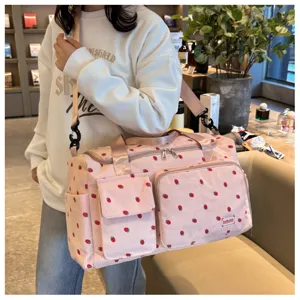 Detailed view of pink corduroy travel duffle bag with cute strawberry print and pockets.