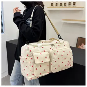 Close-up view of the cute strawberry corduroy travel duffel bag showing multiple front pockets.