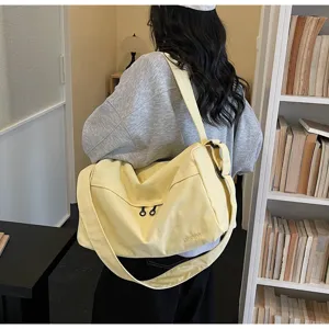 Vue détaillée du sac à bandoulière en toile jaune de grande capacité avec détails pratiques.