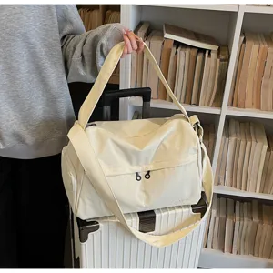 Vue detaille de grand sac de voyage en toile beige avec bandouliere dans scene quotidienne.