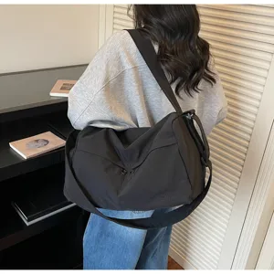 Vue détaillée du grand sac de sport noir, montrant une sangle large et un tissu résistant.