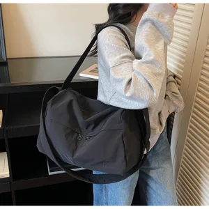 Vue détaillée du sac de voyage noir grand format avec des poches zippées pratiques à l'avant.