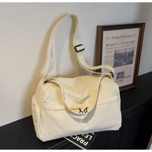 Détail de sac de sport beige grand capacité, montrant la texture de toile et sangle réglable.