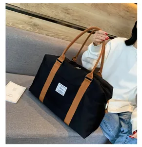 Grand sac de voyage de capacite, sac de sport noir en toile avec poignees marron.