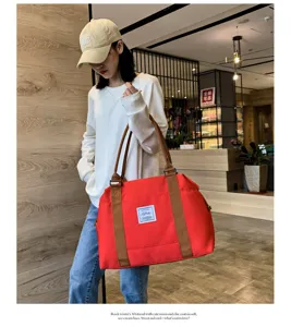 Grand sac de voyage rouge spacieux avec poignées marron et écusson logo élégant.