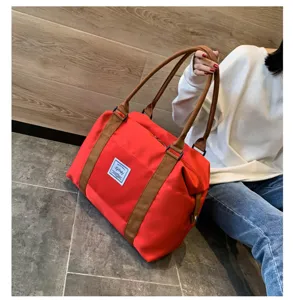 Grand sac de voyage rouge avec des bretelles marron, élégant et portable pour les femmes.