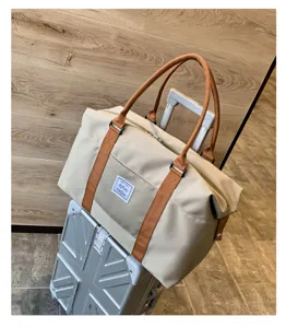 Vue de detail du grand sac de voyage avec poignees marron et tissu beige elegant.