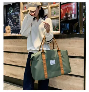 Grand sac de voyage vert avec poignées marron en détail, idéal pour les week-ends.