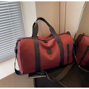 Grand sac de voyage bordeaux avec poignées résistantes et poche zippée avant détaillée.